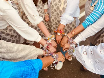 Hands with flower bracelets united in a circle.