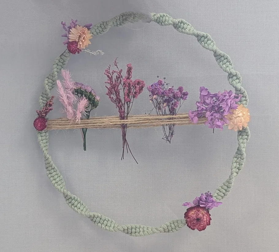 Blumenkranz mit Trockenblumen an Wand.