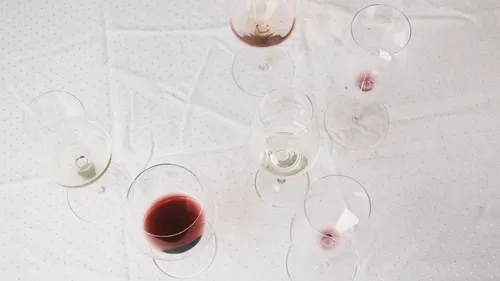 Wine glasses on white tablecloth, various colors.