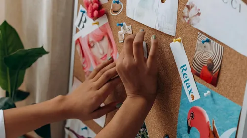 Hands arranging items on a bulletin board.