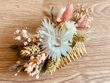 Haarkamm mit getrockneten Blumen auf Holzuntergrund platziert.