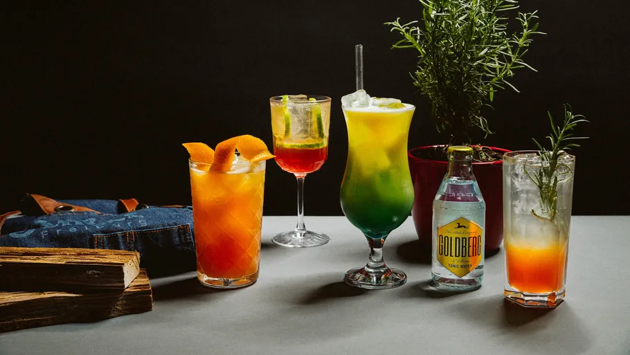 Bunte Cocktails auf Tisch mit Pflanzen.