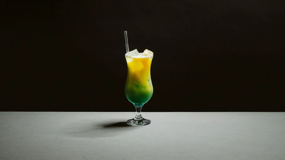 Bunter Cocktail mit Strohhalm auf dunklem Hintergrund.