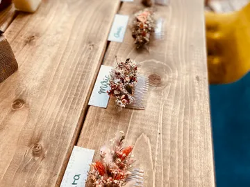 Kämme mit Trockenblumen auf einem Holztablett angeordnet.