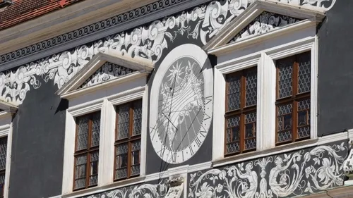 Detailierte Wandmalerei mit Sonnenuhr auf Gebäude.