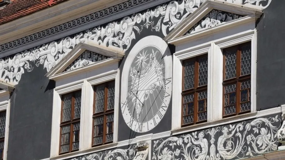 Detailierte Wandmalerei mit Sonnenuhr auf Gebäude.