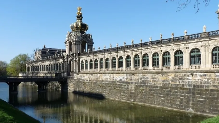 Barockgebäude mit goldgekröntem Turm und Wassergraben.