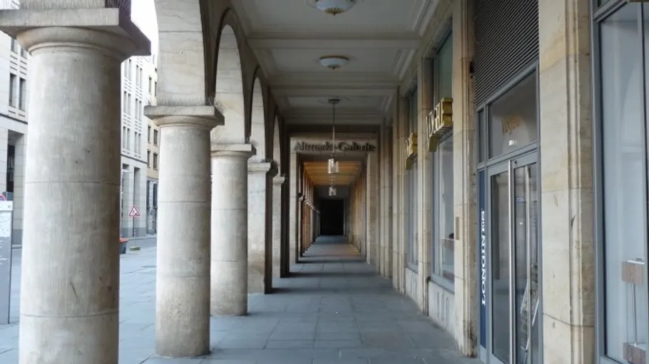 Arched walkway with stone columns, city street.