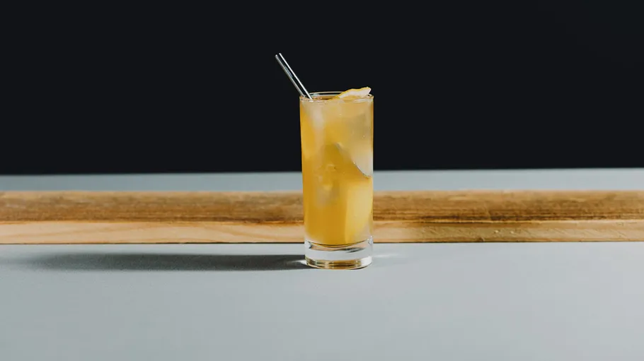 Iced cocktail with straw on wooden table.