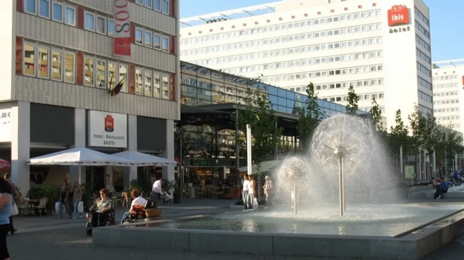 Brunnen spritzt Wasser auf einem Stadtplatz.