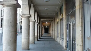 Stone columns line a covered outdoor walkway.