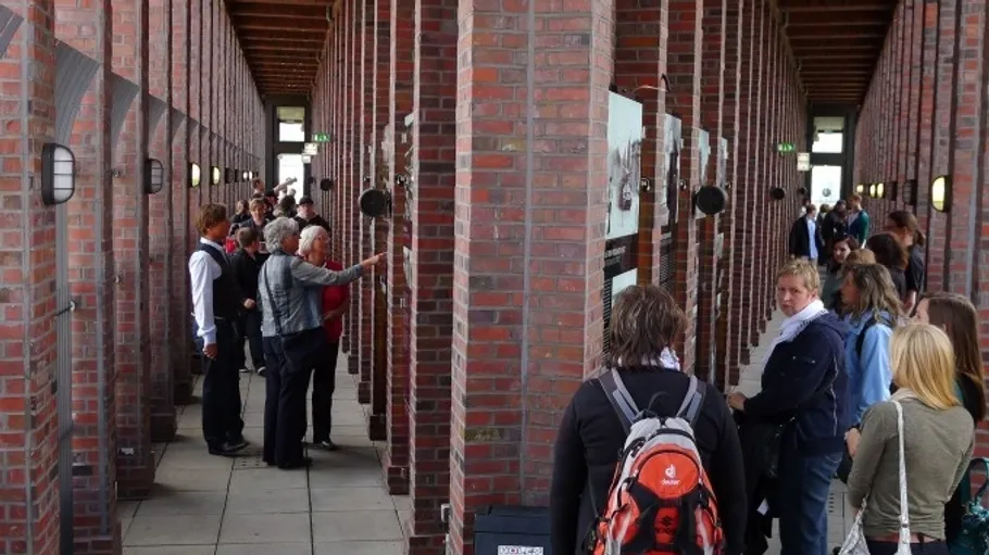 People examining displays in a brick hallway.