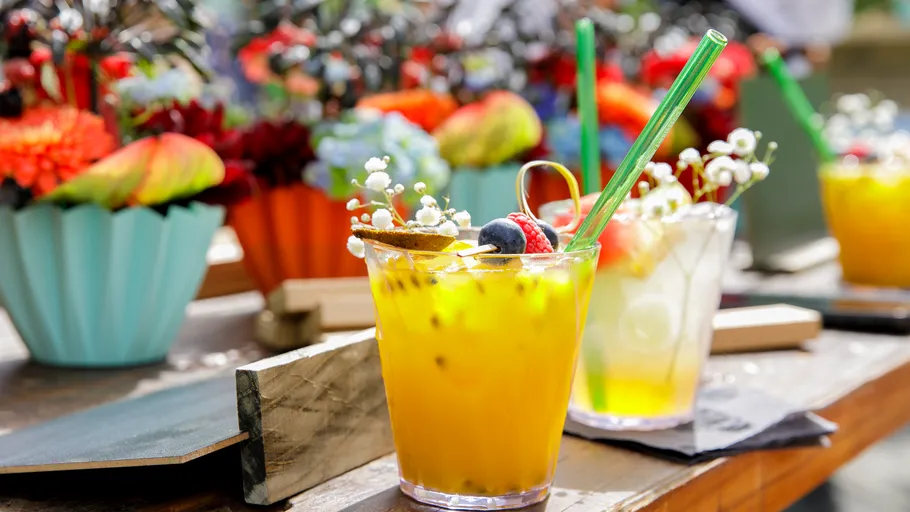 Bunte Cocktails auf Tisch mit Blumen.