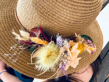A straw hat decorated with colorful, dried flowers.