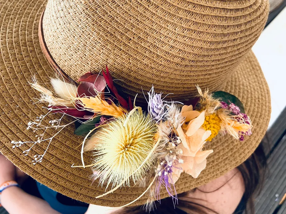 A straw hat decorated with colorful, dried flowers.
