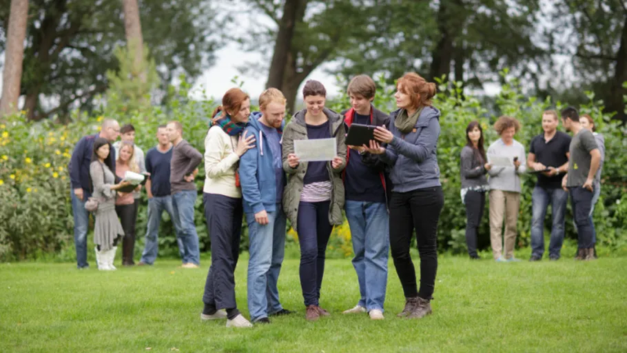 Menschen lesen Karten und Tablets im Park.