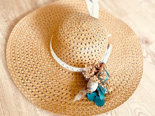 Hat on wooden surface decorated with flowers and ribbon