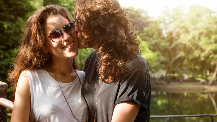 Couple smiling near a sunny pond.