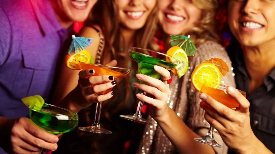 Menschen halten bunte Cocktails auf einer Party.