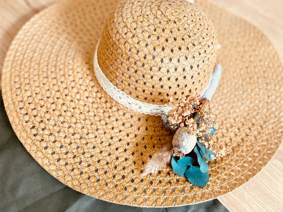 A wide straw hat lies on a soft surface.
