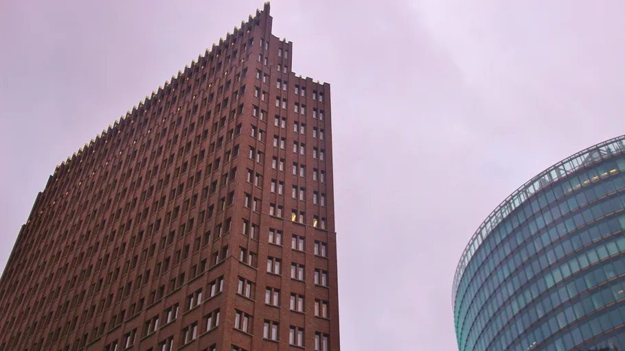 Hohes Backsteingebäude neben Glasstruktur.