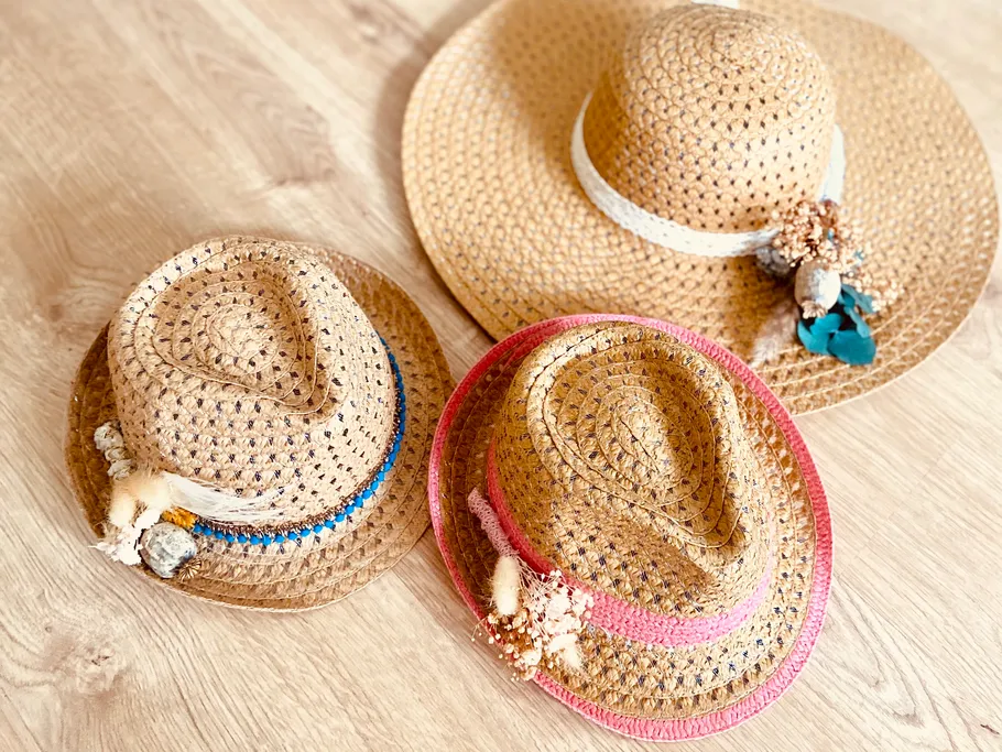 Three straw hats lie on a wooden floor.