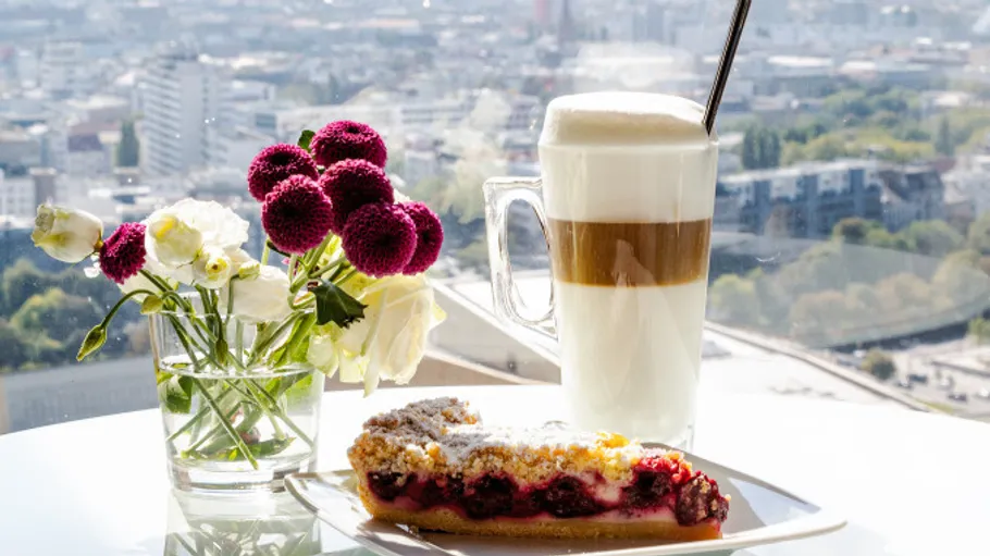 Cake and coffee on table with city view.