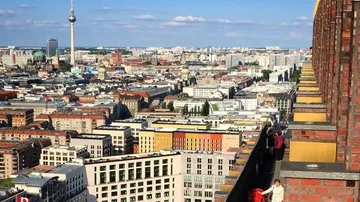 Berliner Stadtszene mit Menschen auf Dachterrasse.
