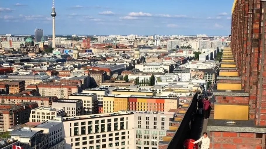 Berliner Stadtszene mit Menschen auf Dachterrasse.