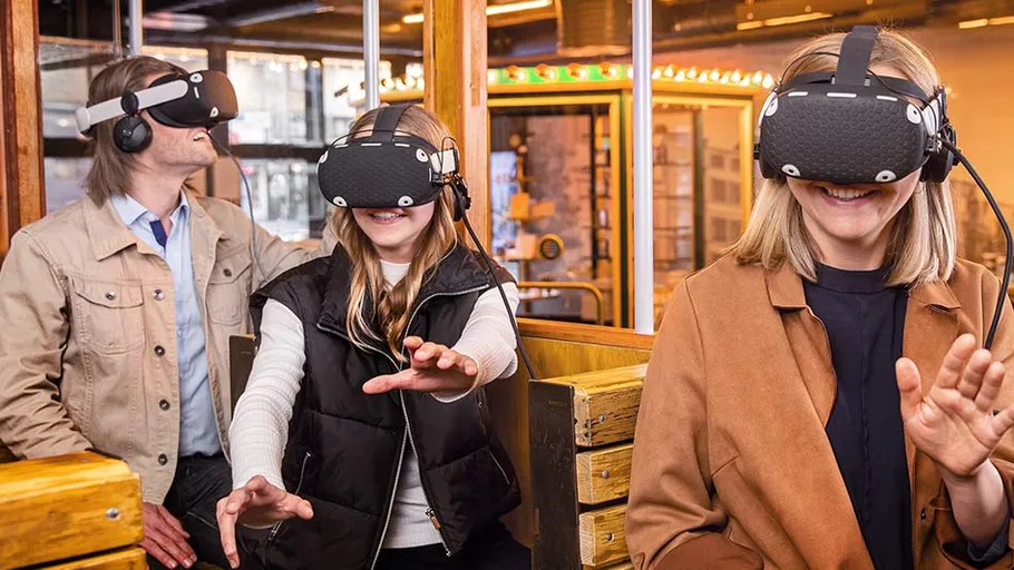 Drei Personen mit VR-Headsets lächeln in einem Raum.