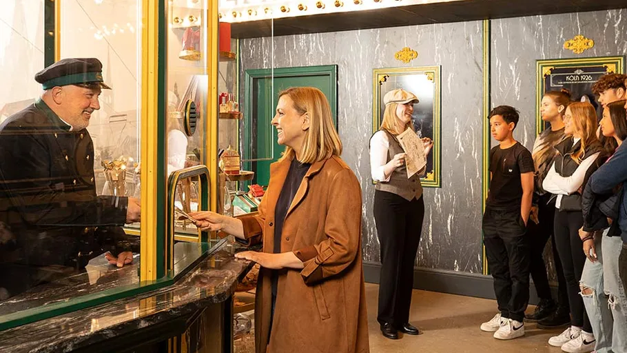 Frau kauft Ticket von kostümiertem Kassierer.
