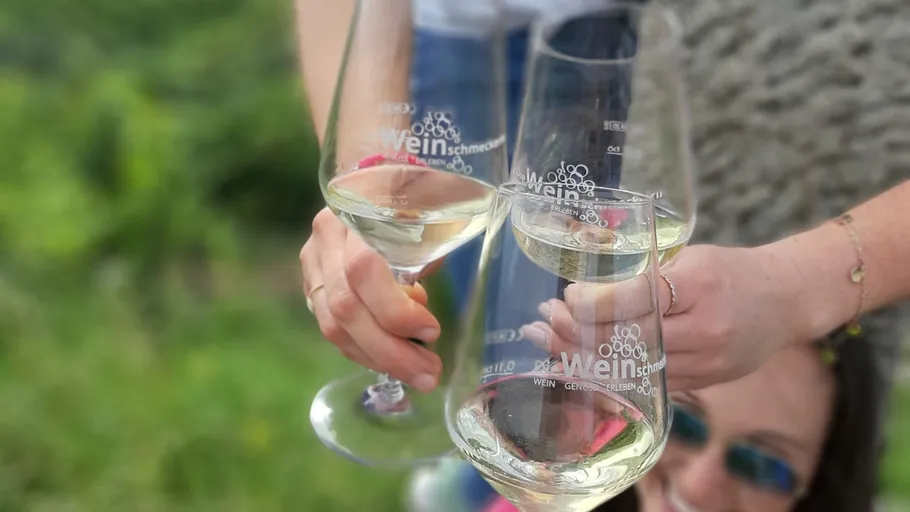 Glasses of white wine raised in celebration outdoors.