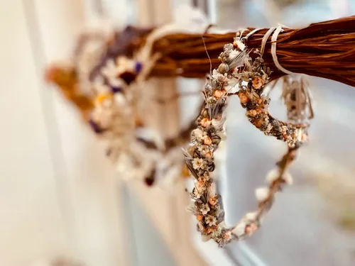 Floral crowns hanging on twigs indoors.
