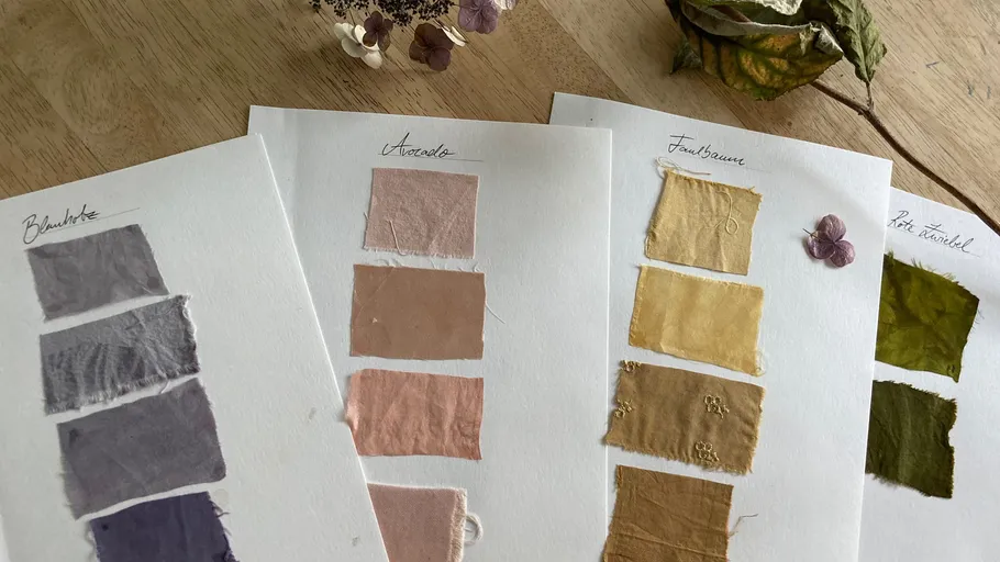 Stoffmuster auf Papier, beschriftet, auf Tisch angezeigt.