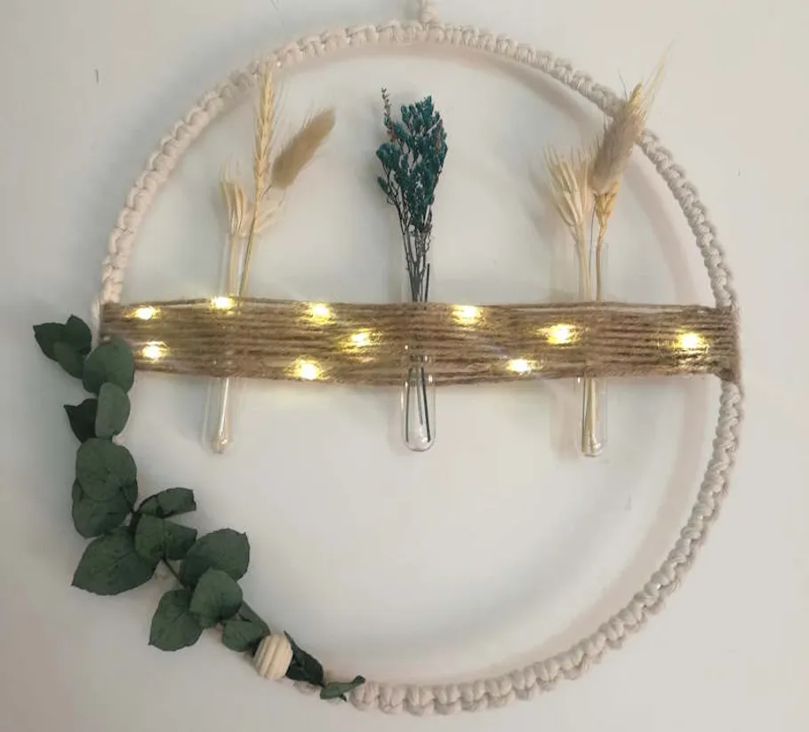 Decorative wreath with lights, plants, and dried flowers.