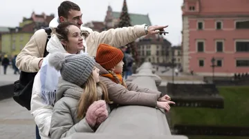 Family sightseeing in city, pointing and smiling.