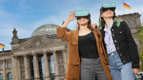 Zwei Personen mit VR-Brillen vor historischem Gebäude.