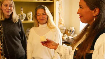 Three women talking in a pottery shop.