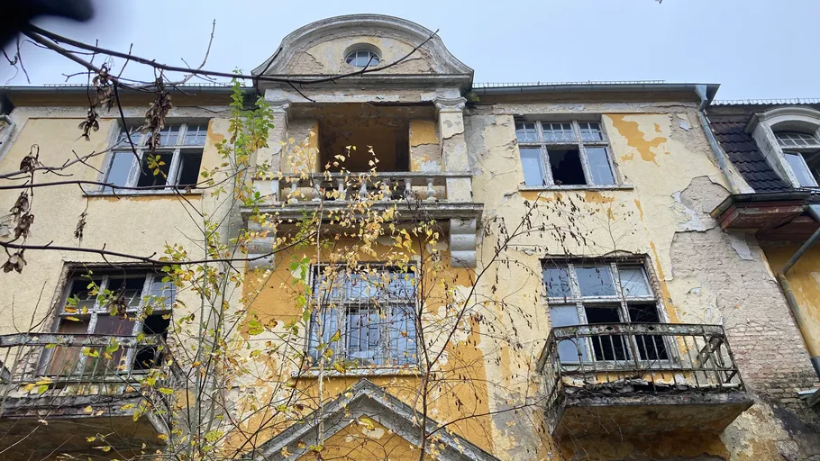 Verfallenes Gebäude mit kaputten Fenstern, gelbe Fassade.