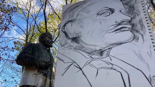 Statue next to detailed pencil drawing outdoors.