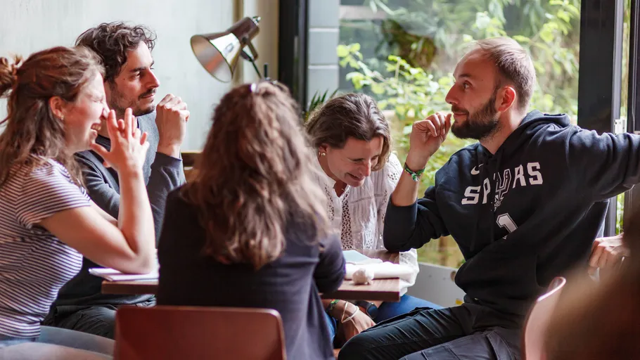Group of people talking at a table indoors.