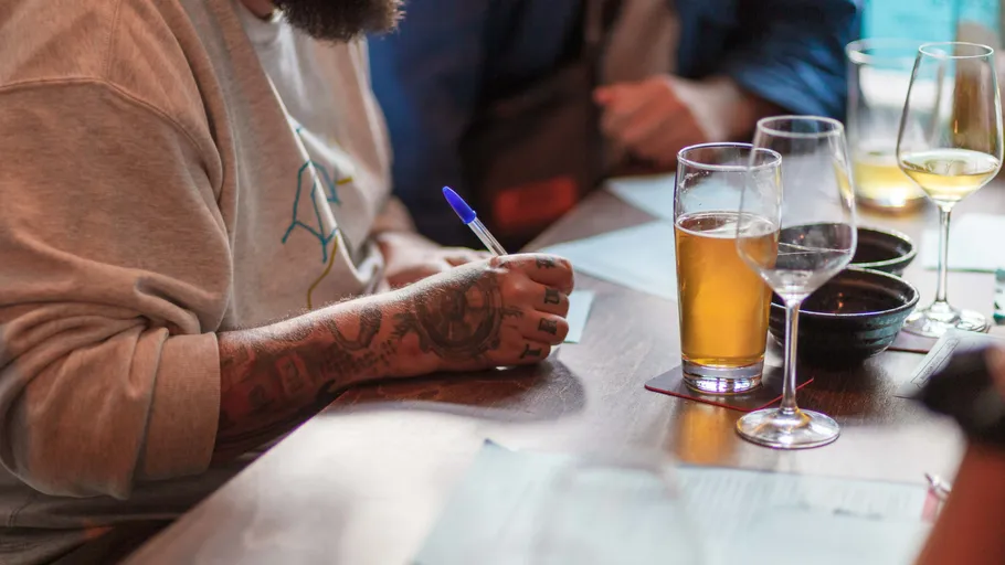 Person schreibt auf Papier neben Biergläsern.