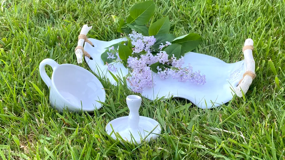 White ceramics and flowers on grass.