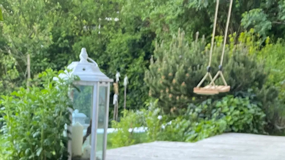 Laterne und Schaukel in einem grünen Garten.
