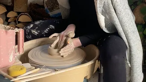Person shaping clay on a pottery wheel.