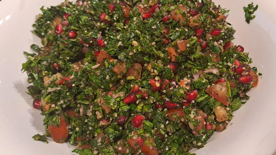 Tabbouleh salad with parsley, tomatoes, pomegranate seeds.