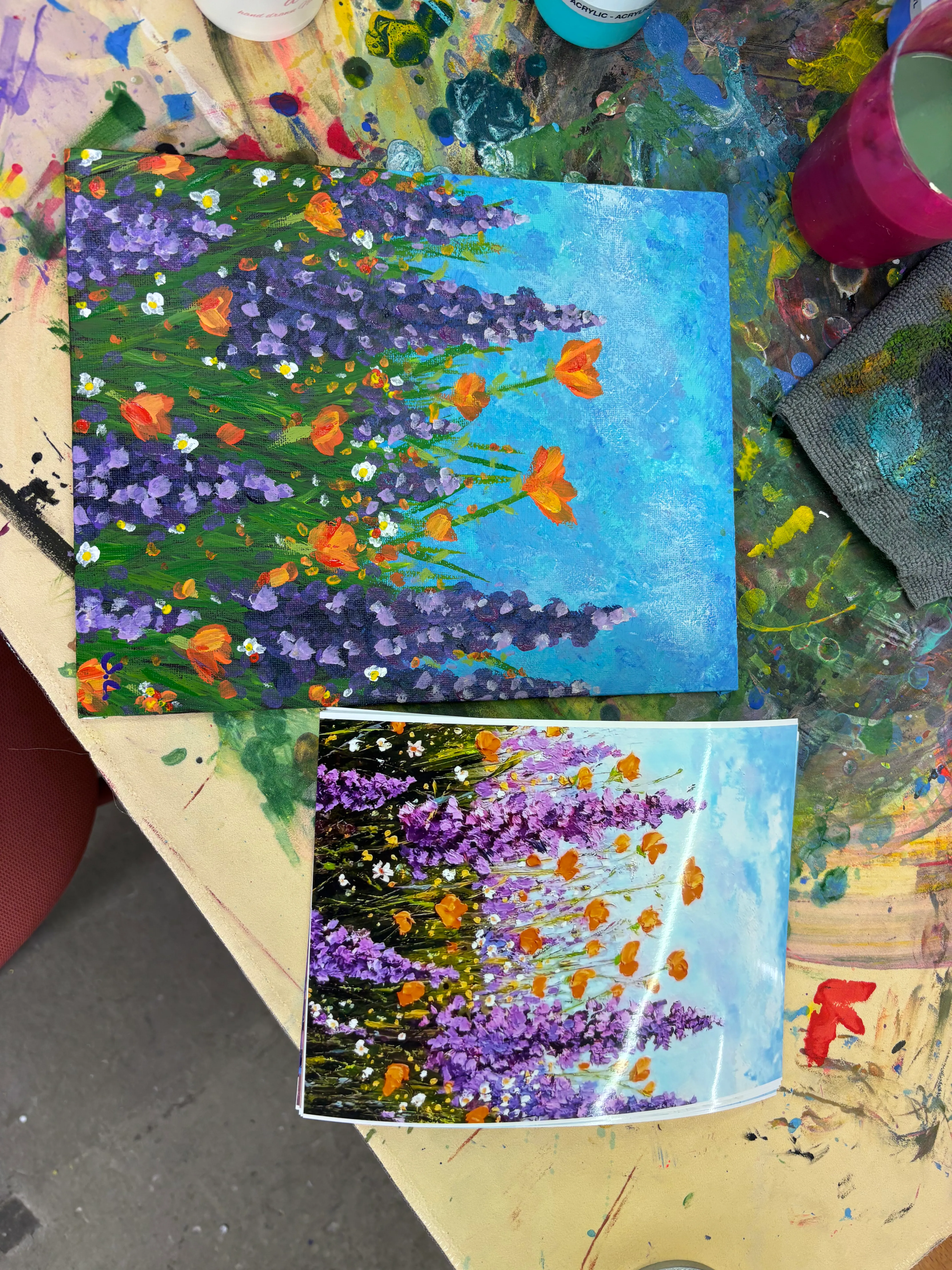 Zwei Blumenbilder auf buntem Tisch.