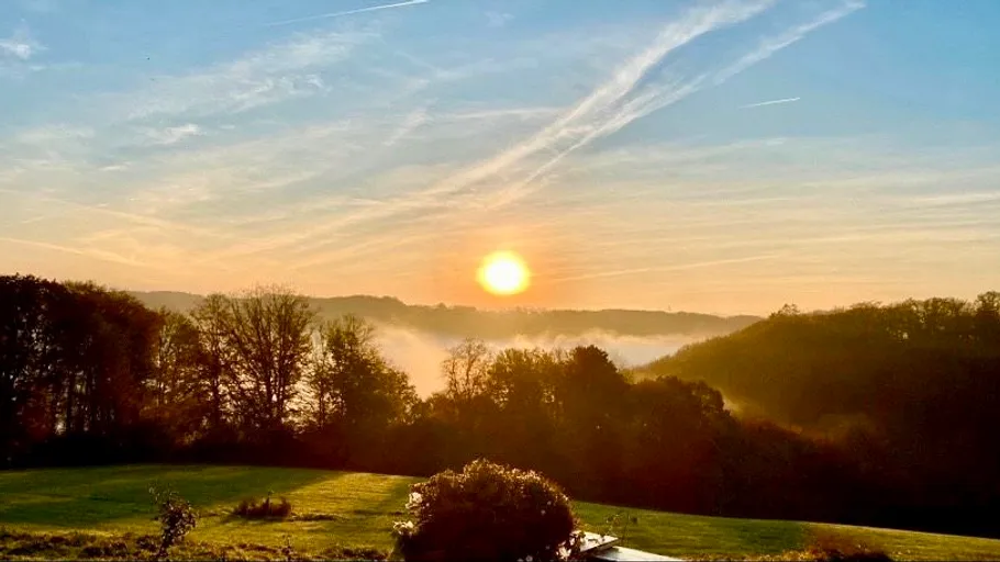 Sonnenaufgang über nebligen bewaldeten Hügeln.