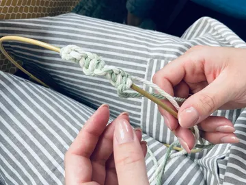 Braid hands with wool in a striped environment.