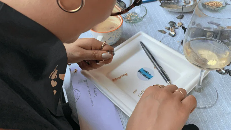 Person stellt Schmuck an einem Tisch her.